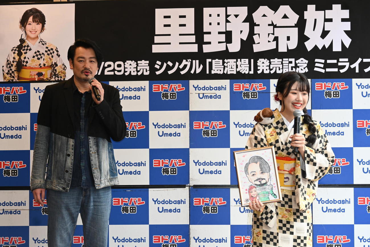 高校の後輩で演歌歌手の里野鈴妹（右）が描いた似顔絵に笑顔の小田井涼平（撮影・松浦隆司）