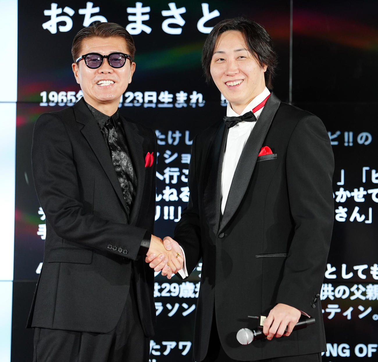 「LAST CALL」制作発表会で握手を交わすおちまさと氏（左）と溝口勇児氏（撮影・清水貴仁）