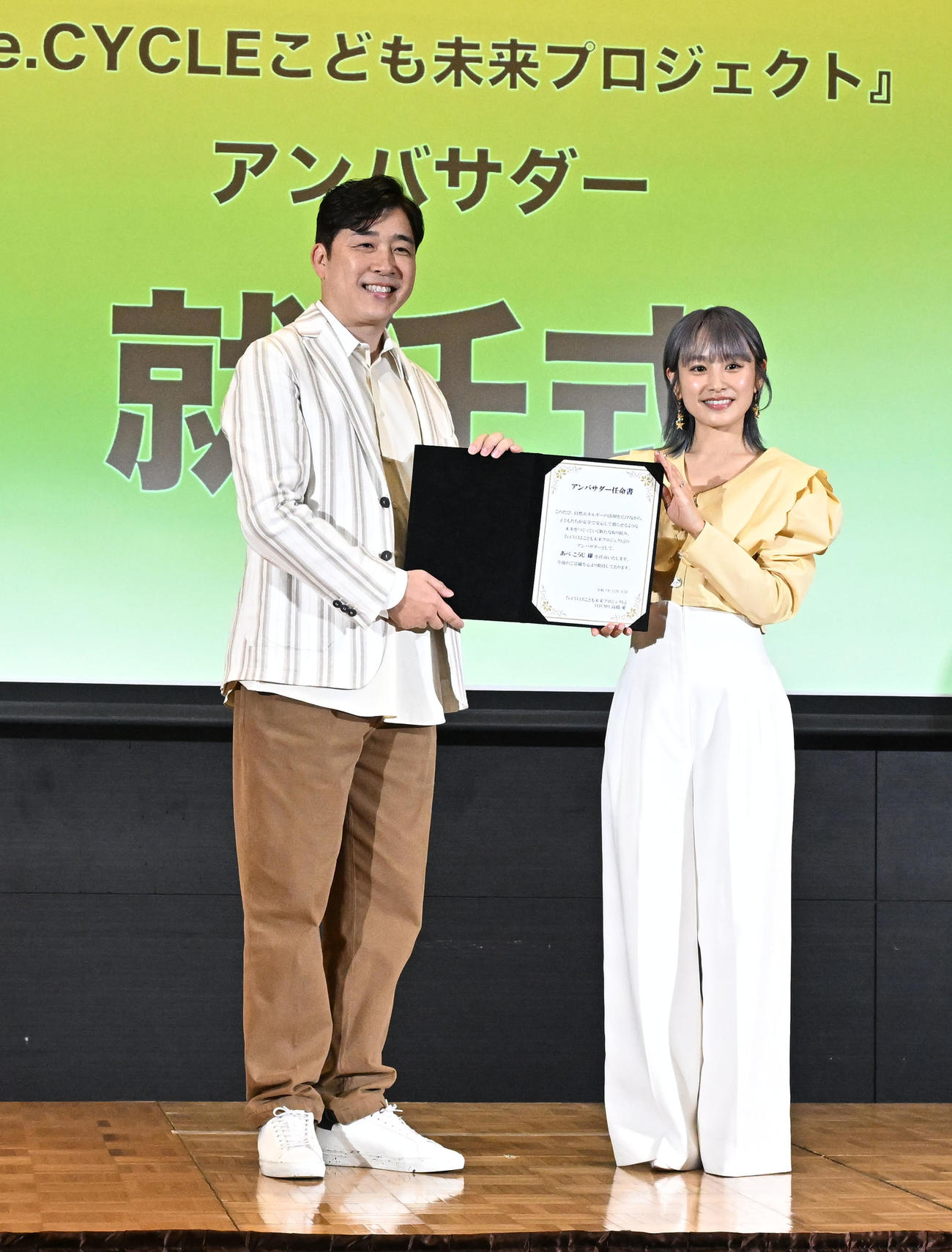 「Pikaでんきローンチイベント」でアンバサダー任命書を手に写真撮影に応じるあべこうじと高橋愛夫妻（撮影・千葉一成）