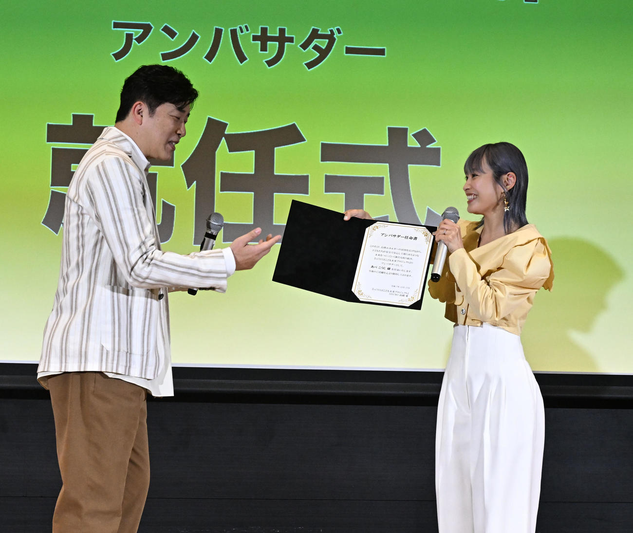 「Pikaでんきローンチイベント」であべこうじにアンバサダー任命書を手渡す高橋愛（撮影・千葉一成）