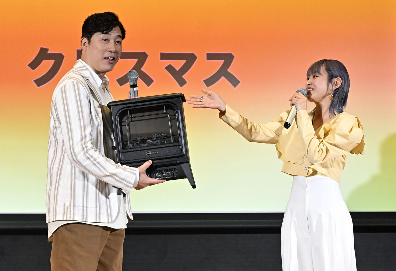 「Pikaでんきローンチイベント」であべこうじ（左）にクリスマスプレゼントの電気暖炉を用意した高橋愛（撮影・千葉一成）