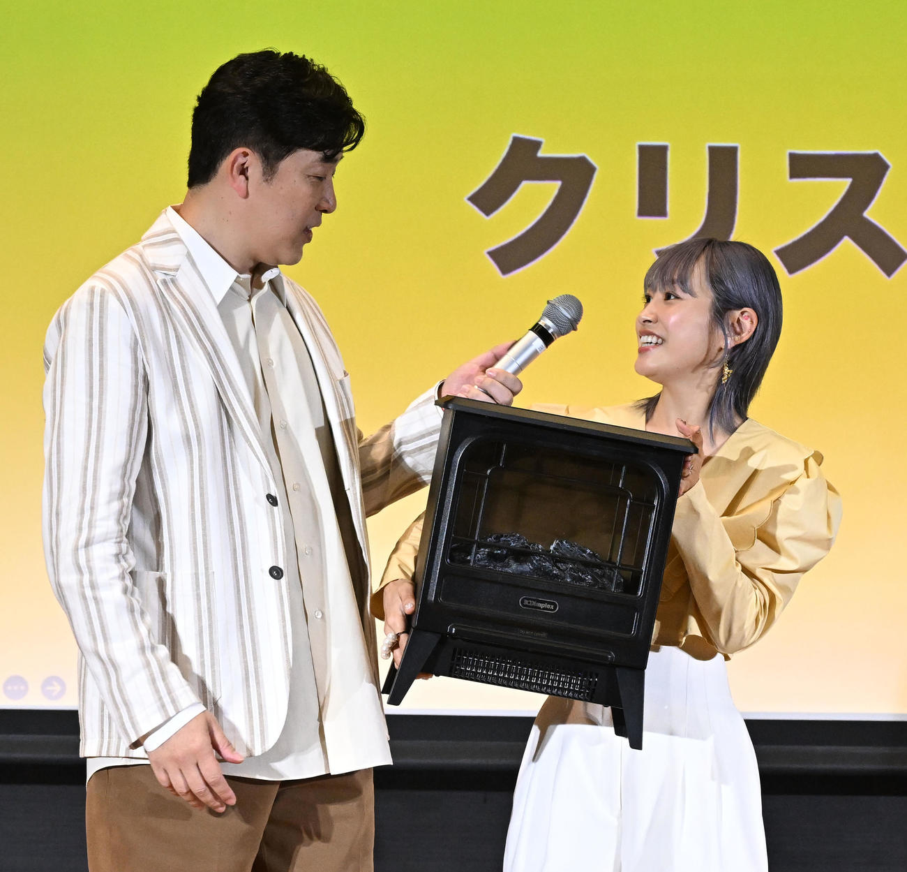 「Pikaでんきローンチイベント」であべこうじ（左）にクリスマスプレゼントの電気暖炉を用意した高橋愛（撮影・千葉一成）