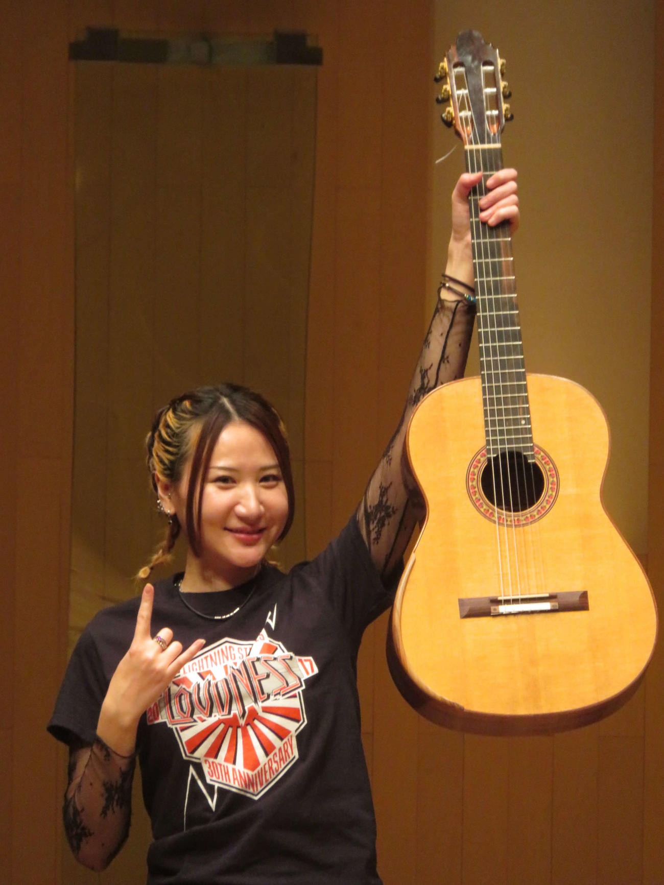 LOUDNESSTシャツに身を包み、メロックサインでギターを掲げる猪居亜美（撮影・川田和博）