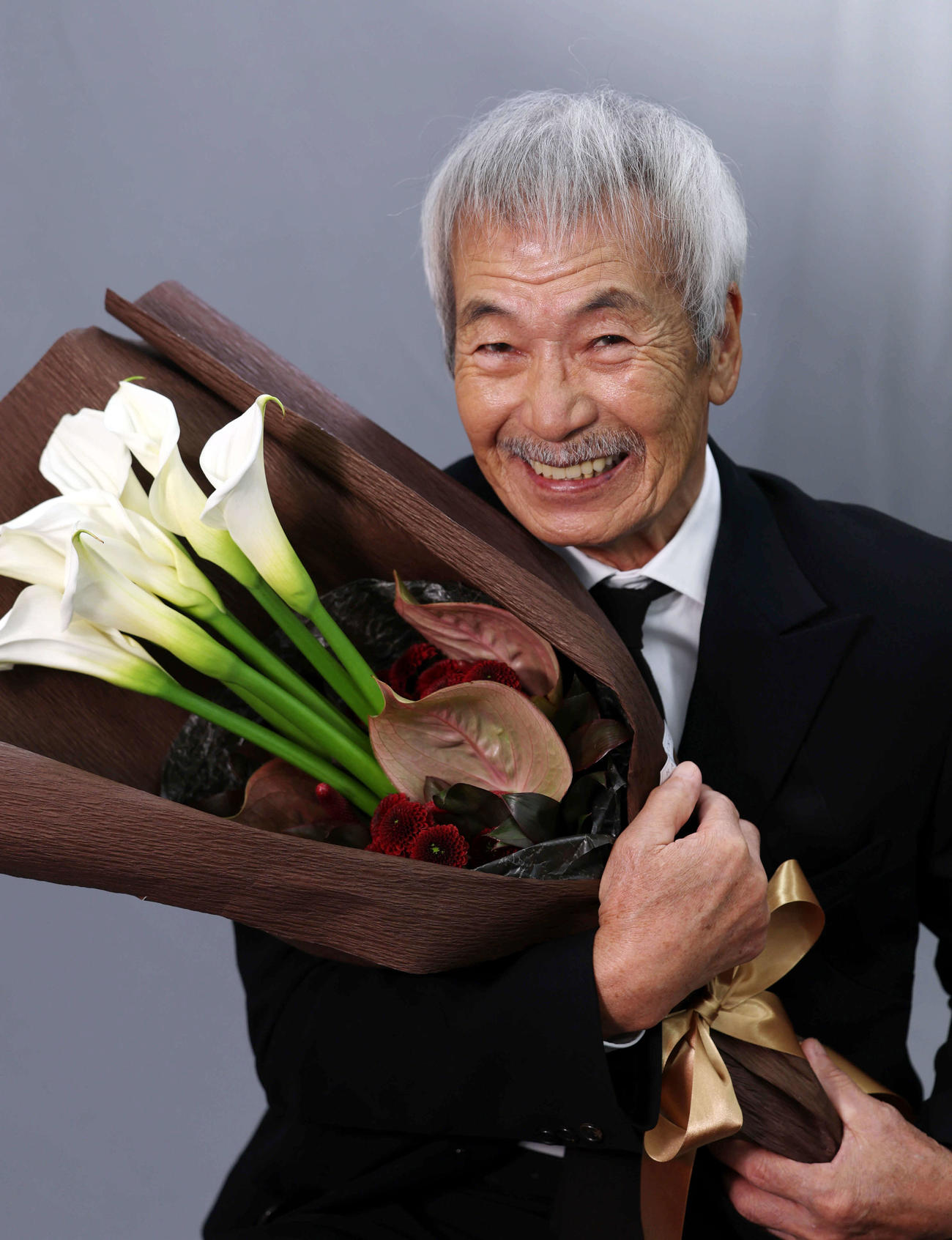 助演男優賞を受賞した田中泯は花束を抱きかかえるようにして笑顔を見せる（2025年12月撮影）