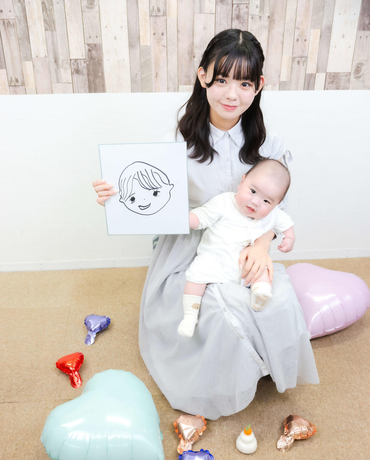 夫の似顔絵を手に赤ちゃんと写真に納まる宮里莉羅（撮影・河田真司）