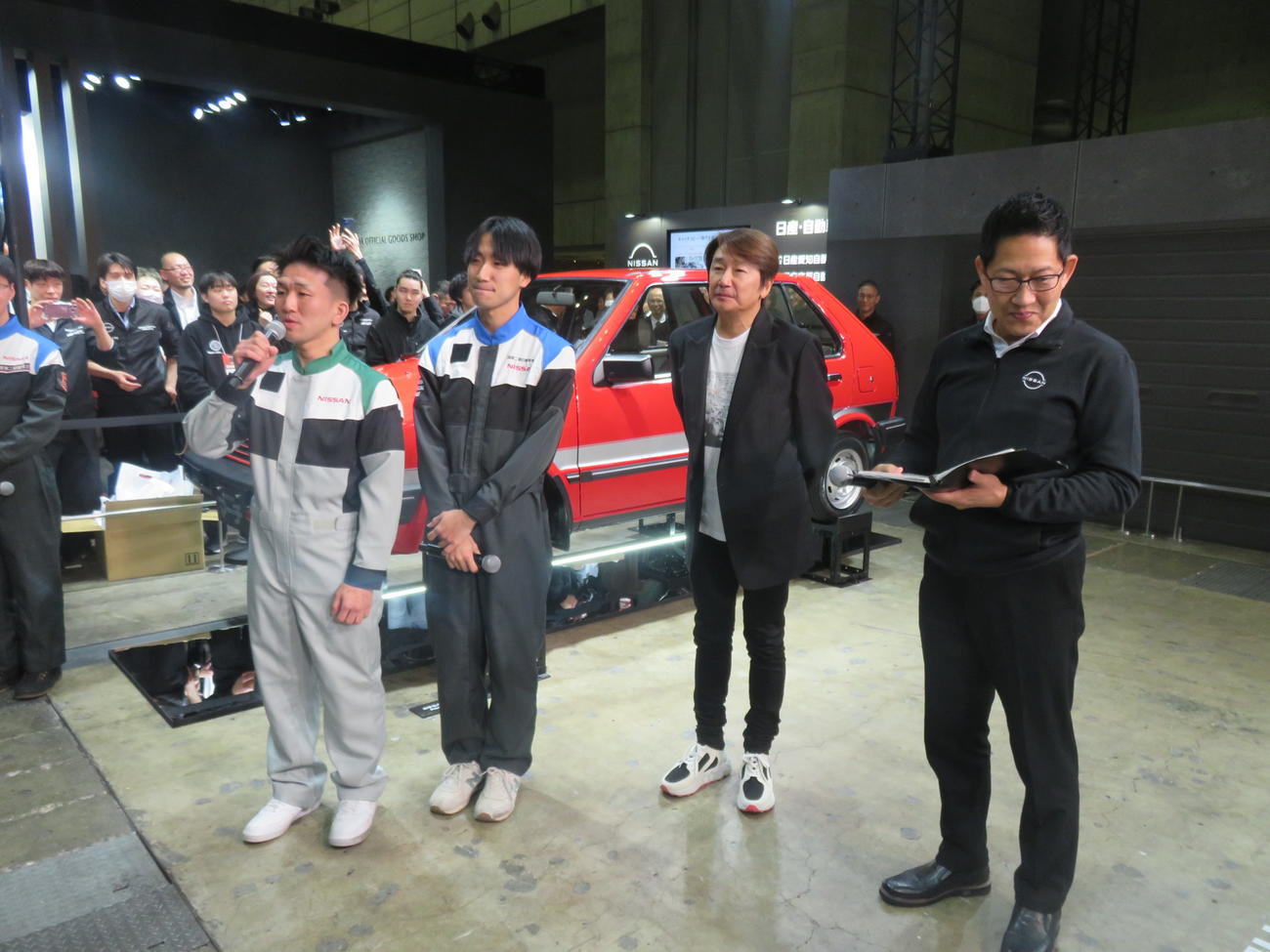 千葉・幕張メッセで開幕した東京オートサロンの日産ブースで日産自動車大学の生徒たちがレストアした赤い初代マーチを紹介する近藤真彦（左から3人目）