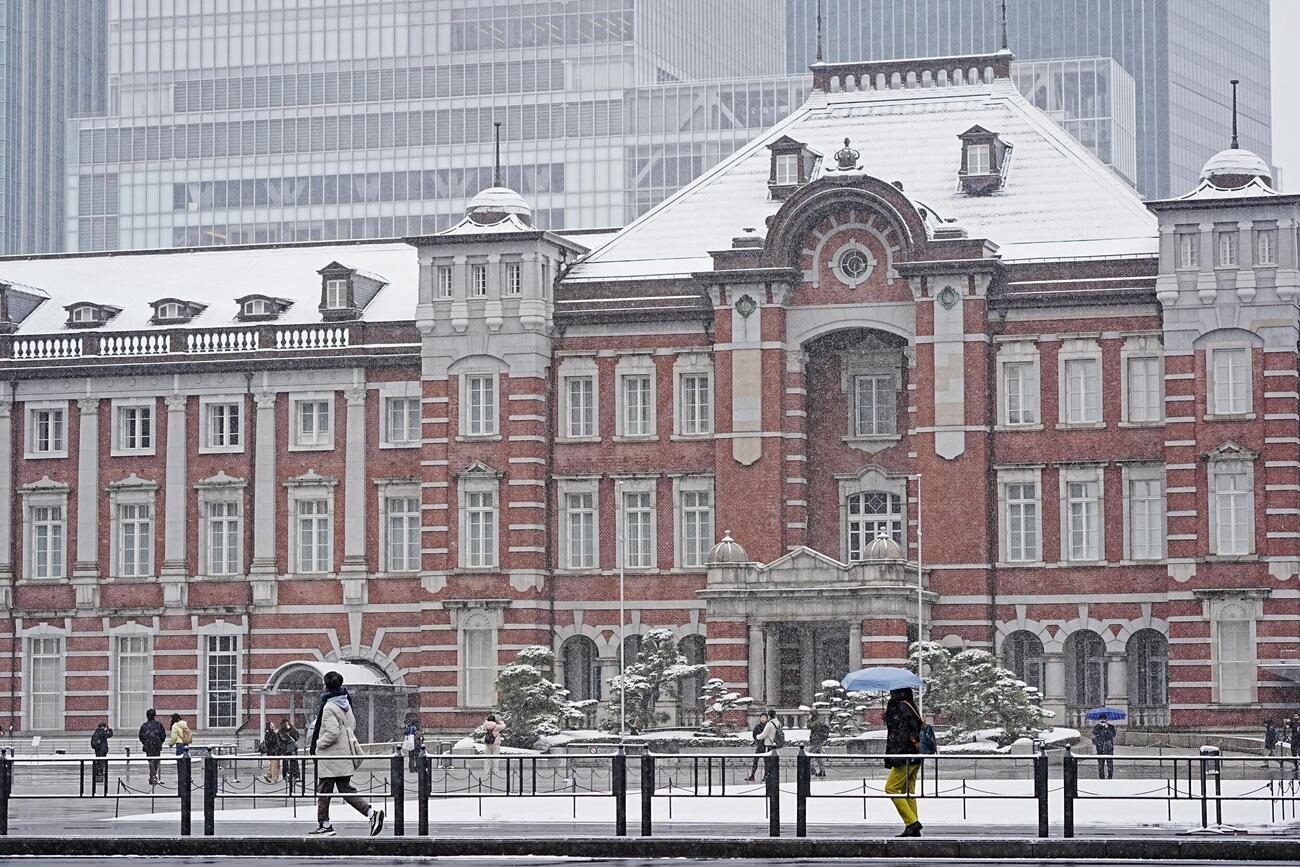 雪が降る中、JR東京駅前を訪れた人たち（共同）