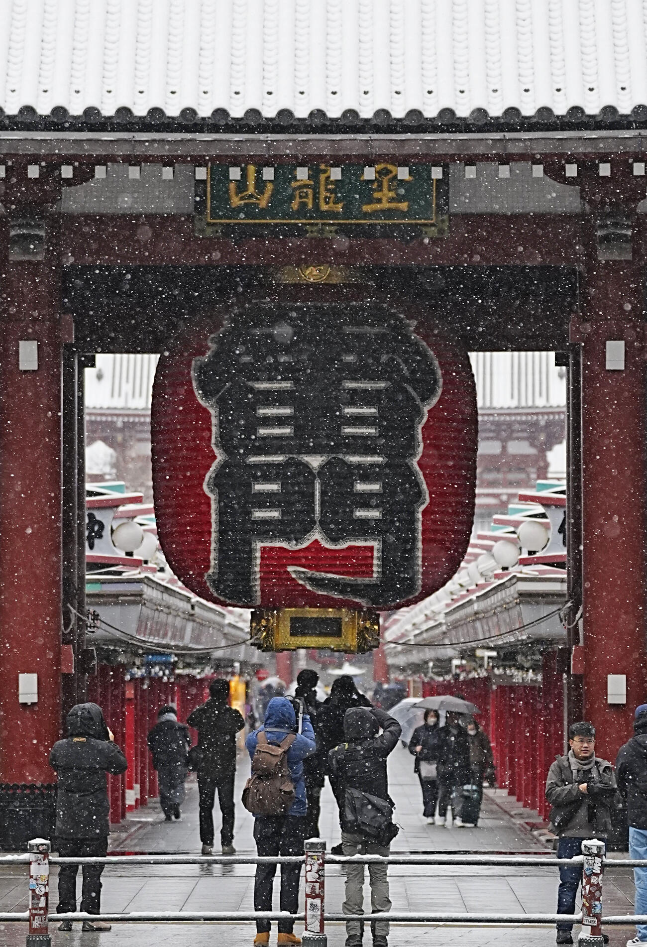 雪が降る中、東京・浅草寺の雷門を訪れた人たち（共同）