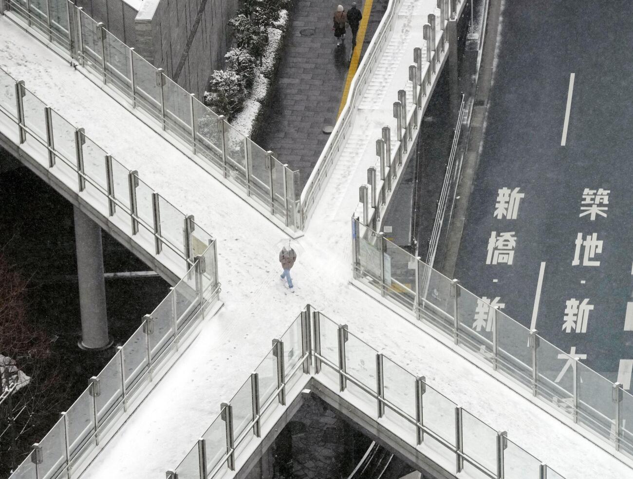 うっすらと積もった雪の中を歩く人＝8日午前、東京都港区（共同）