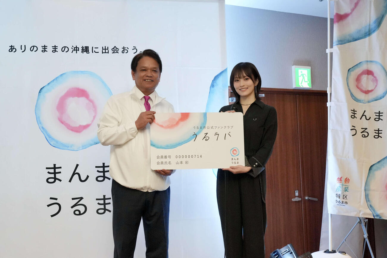 うるま市の中村正人市長（左）から「うるラバ」会員証を受け取る山本彩