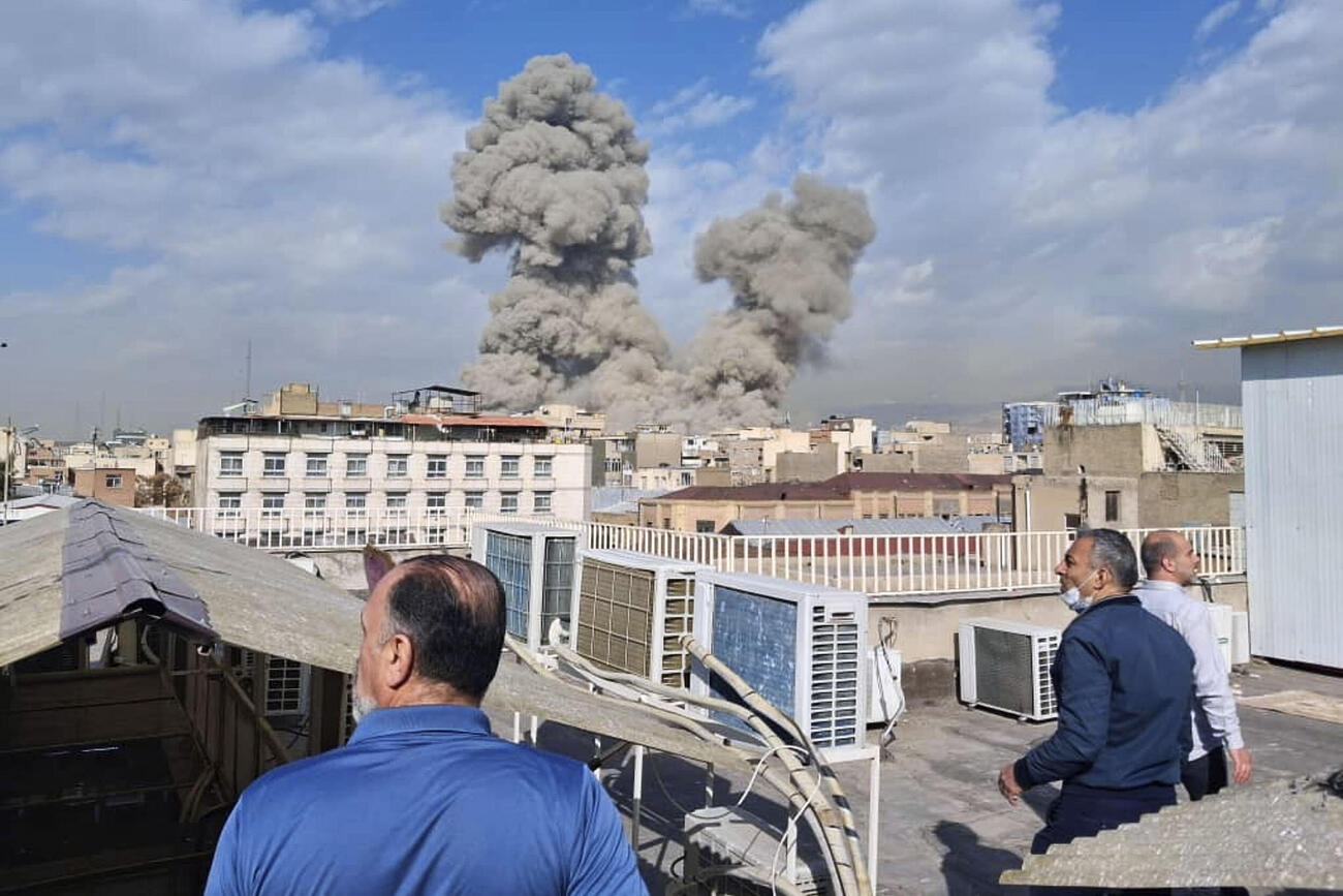 イランの首都テヘランで爆発後に立ち上る煙を見る人たち＝28日（AP＝共同）