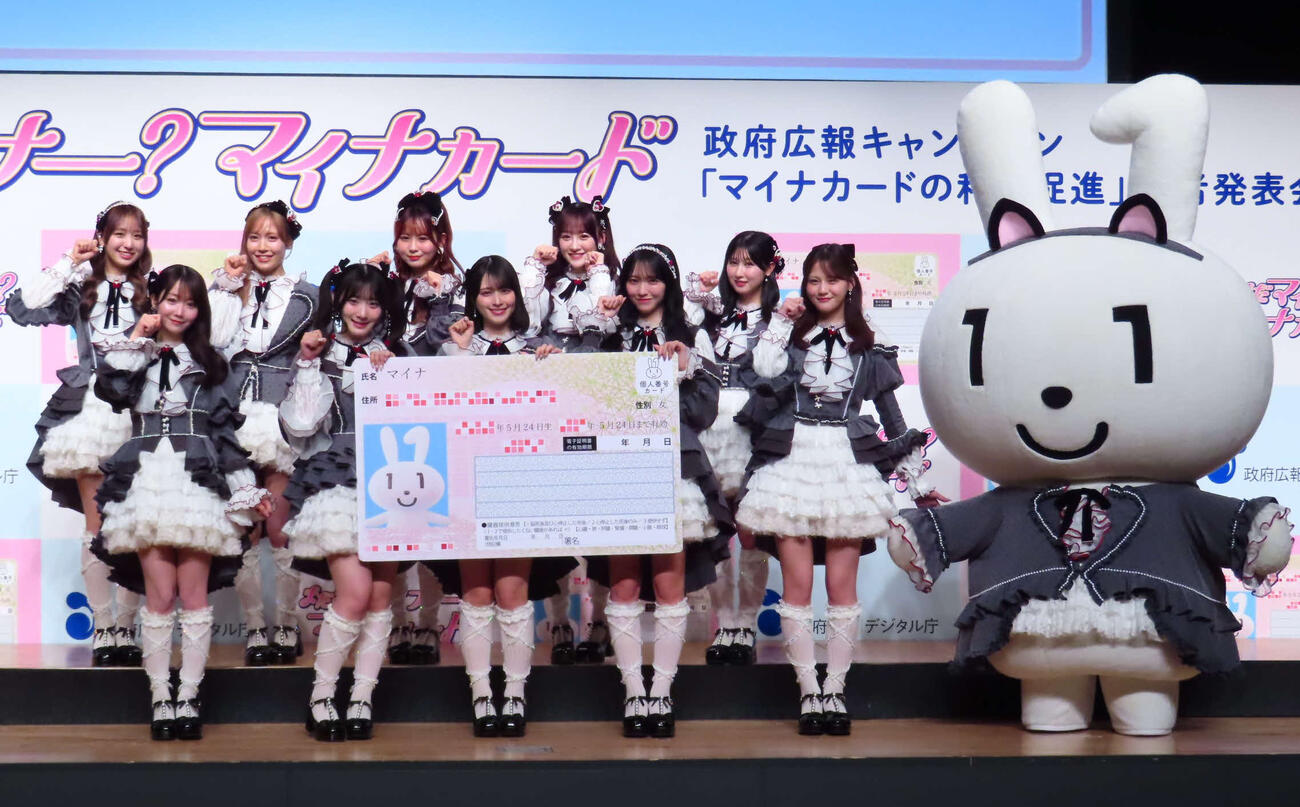 「マイナカードの利用促進」記者発表会に出席した＝LOVE。左から瀧脇笙古、大谷映美里、諸橋沙夏、齋藤樹愛羅、大場花菜、佐々木舞香、音嶋莉沙、野口衣織、山本杏奈、髙松瞳、マイナちゃん