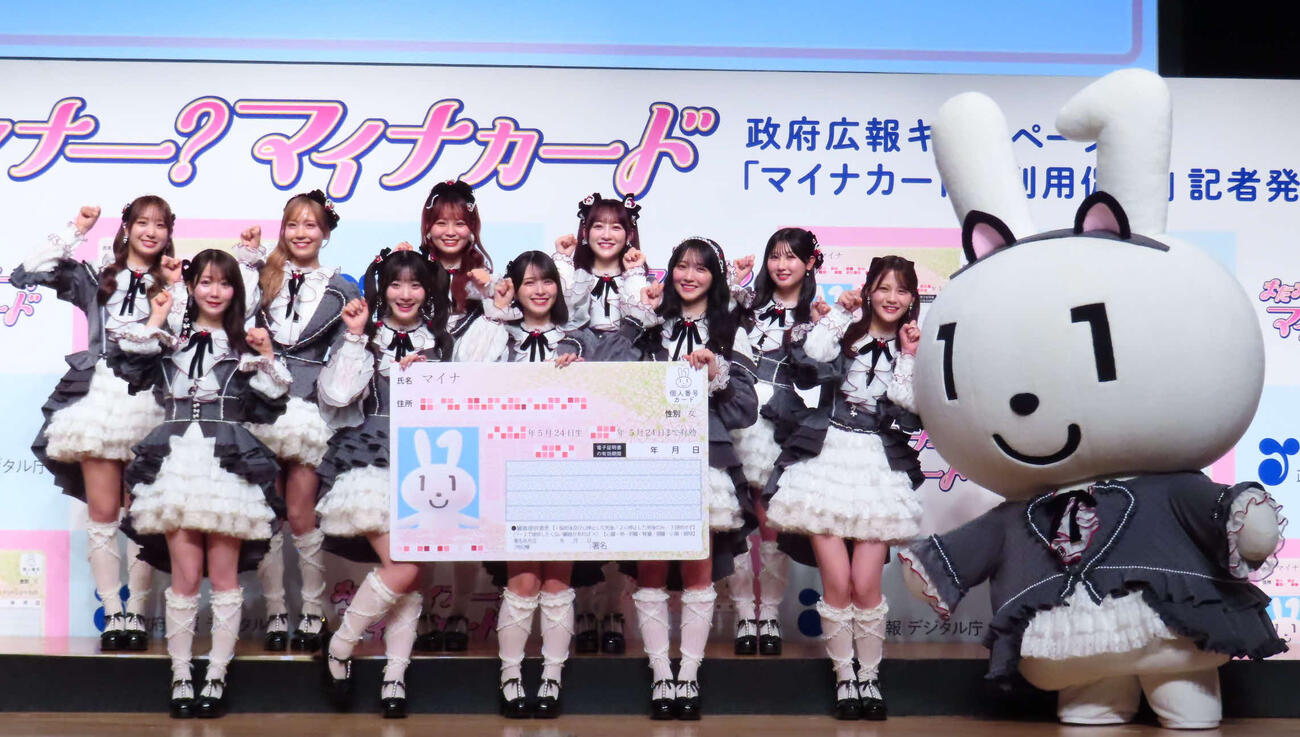 「マイナカードの利用促進」記者発表会に出席した＝LOVE。左から瀧脇笙古、大谷映美里、諸橋沙夏、齋藤樹愛羅、大場花菜、佐々木舞香、音嶋莉沙、野口衣織、山本杏奈、髙松瞳、マイナちゃん