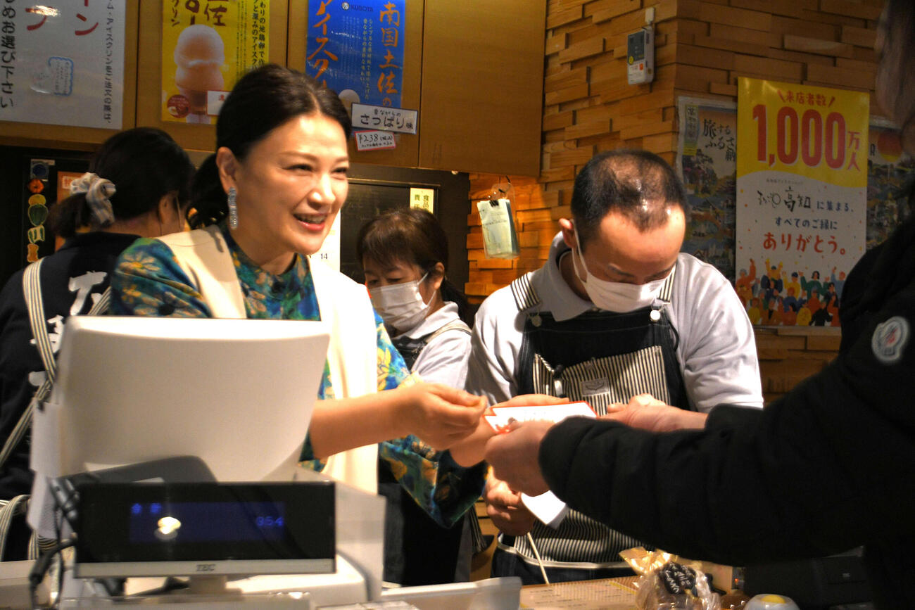 高知県アンテナショップ「まるごと高知」来店1000万人を記念したイベントで同店のレジに入って感謝の意を伝える同県観光特使の島崎和歌子
