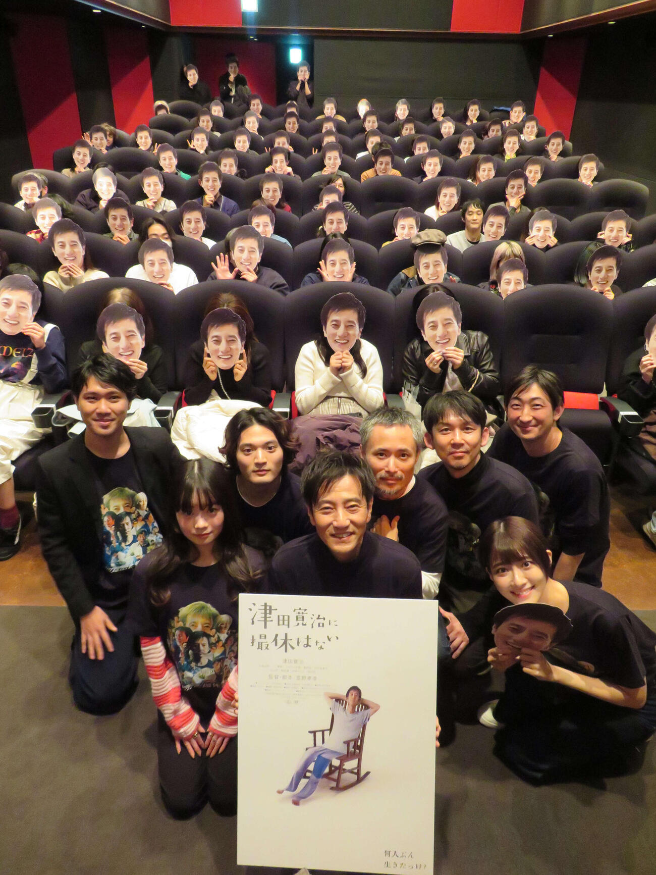 映画「津田寛治に撮休はない」第2弾先行上映舞台あいさつで、津田寛治お面をかぶった客席をバックに撮影する、前列左から平澤由理、津田寛治、中村祐美子、後列左から萱野孝幸監督、篠田諒、こばやし元樹、松林慎司、園山敬介（撮影・村上幸将）