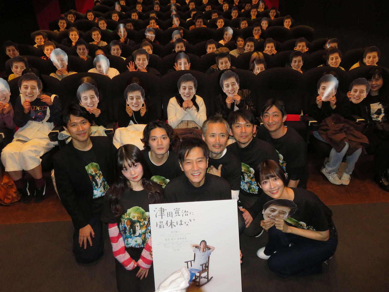映画「津田寛治に撮休はない」第2弾先行上映舞台あいさつで、津田寛治お面をかぶった客席をバックに撮影する、前列左から平澤由理、津田寛治、中村祐美子、後列左から萱野孝幸監督、篠田諒、こばやし元樹、松林慎司、園山敬介（撮影・村上幸将）