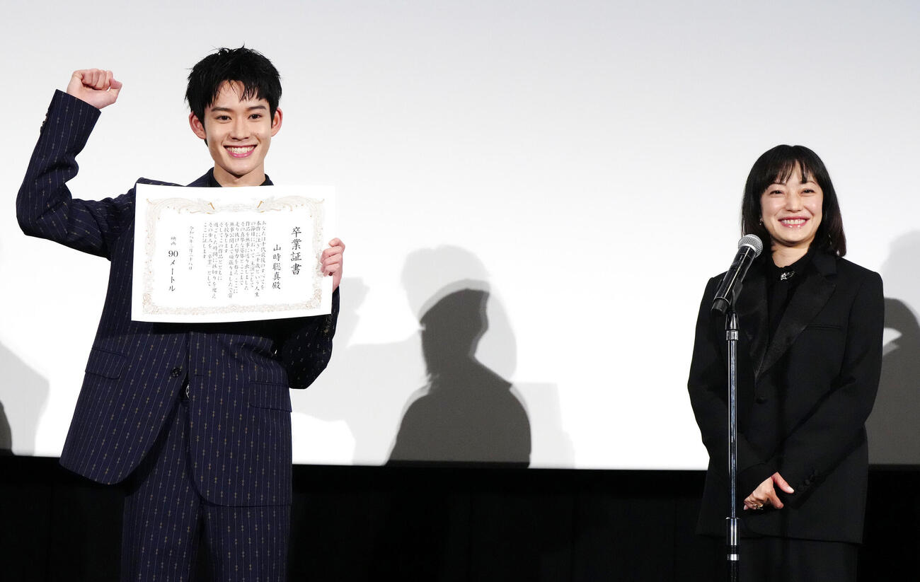 映画「90メートル」公開記念舞台あいさつで卒業証書を授与されガッツポーズの山時聡真（左）。右は菅野美穂（撮影・江口和貴）