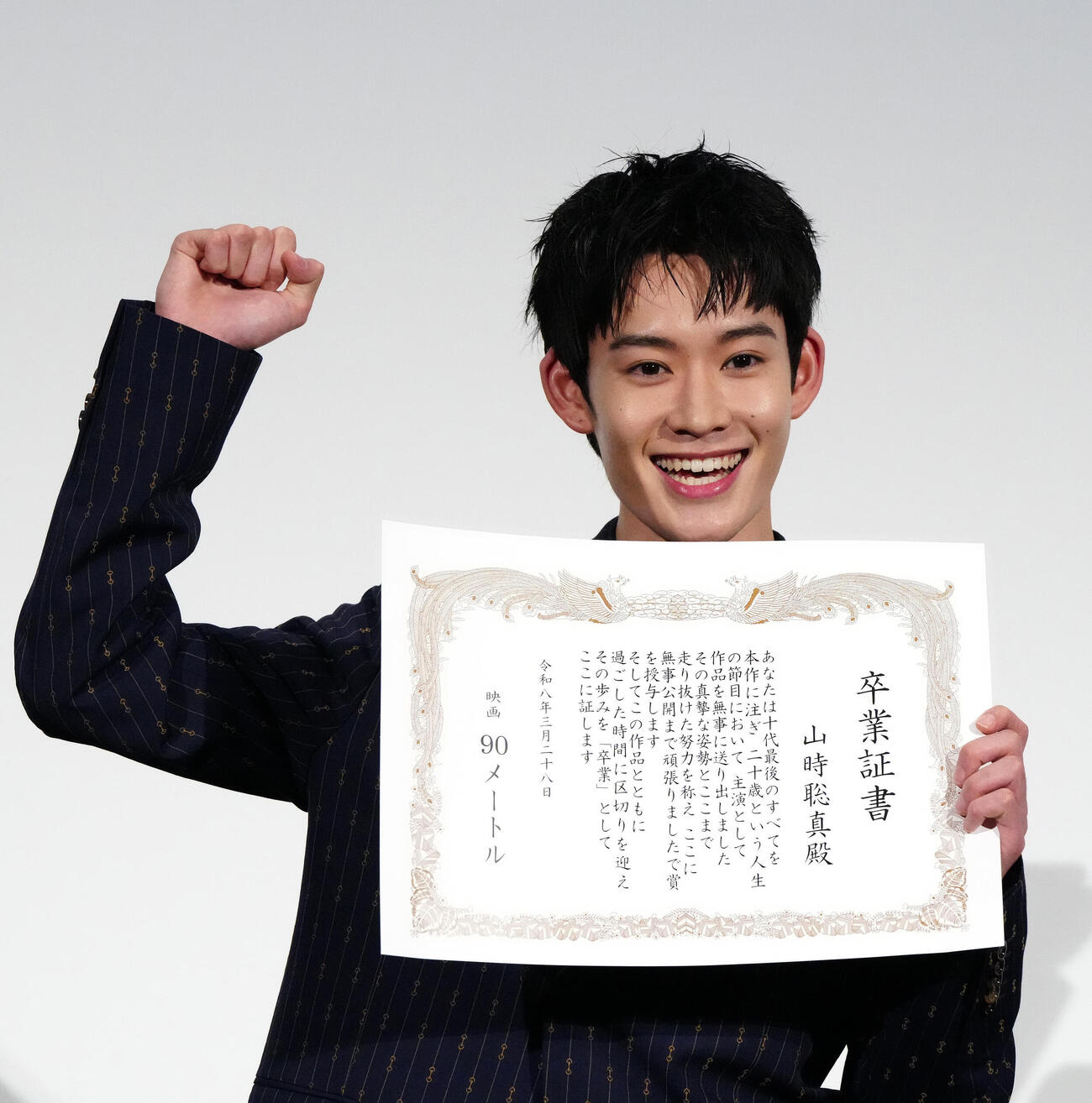 映画「90メートル」公開記念舞台あいさつで卒業証書を授与されガッツポーズの山時聡真（撮影・江口和貴）