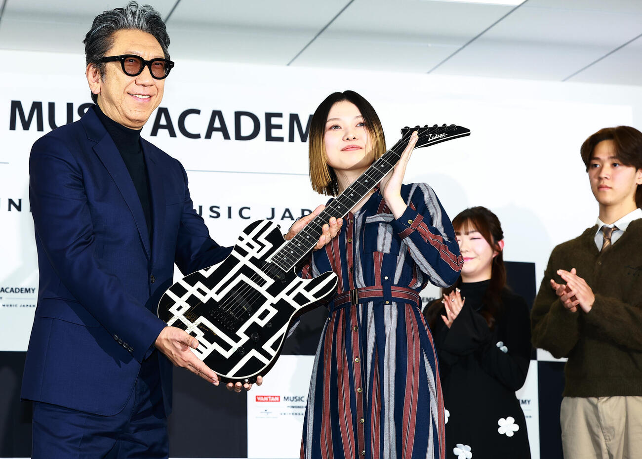 「バンタンミュージックアカデミー　POWERED BY　ユニバーサルミュージック」の開校イベントに登場した特別顧問の布袋寅泰（左）は、入校予定の代表者にギターを贈呈（撮影・野上伸悟）