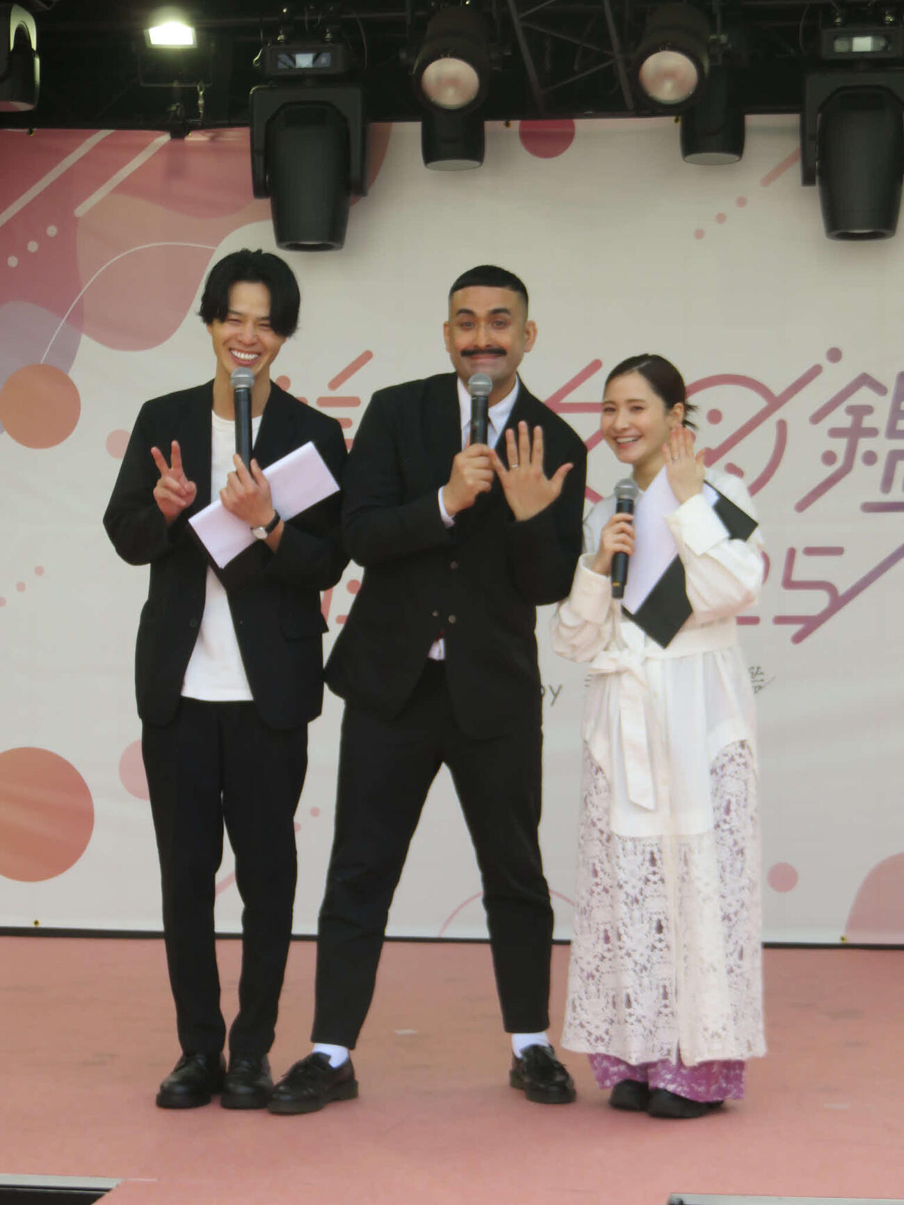 デニス植野行雄（中）と比嘉梨乃（右）は左手薬指の毛コン指波を見せる。左は松下宣夫