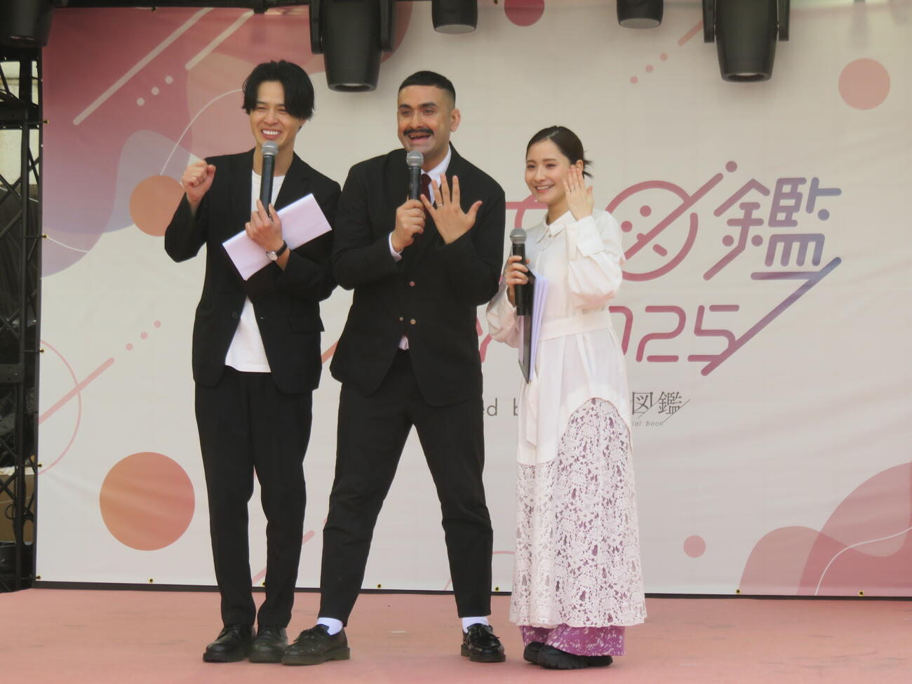 デニス植野行雄（中）と比嘉梨乃（右）は左手薬指の結婚指輪を見せる。左は松下宣夫