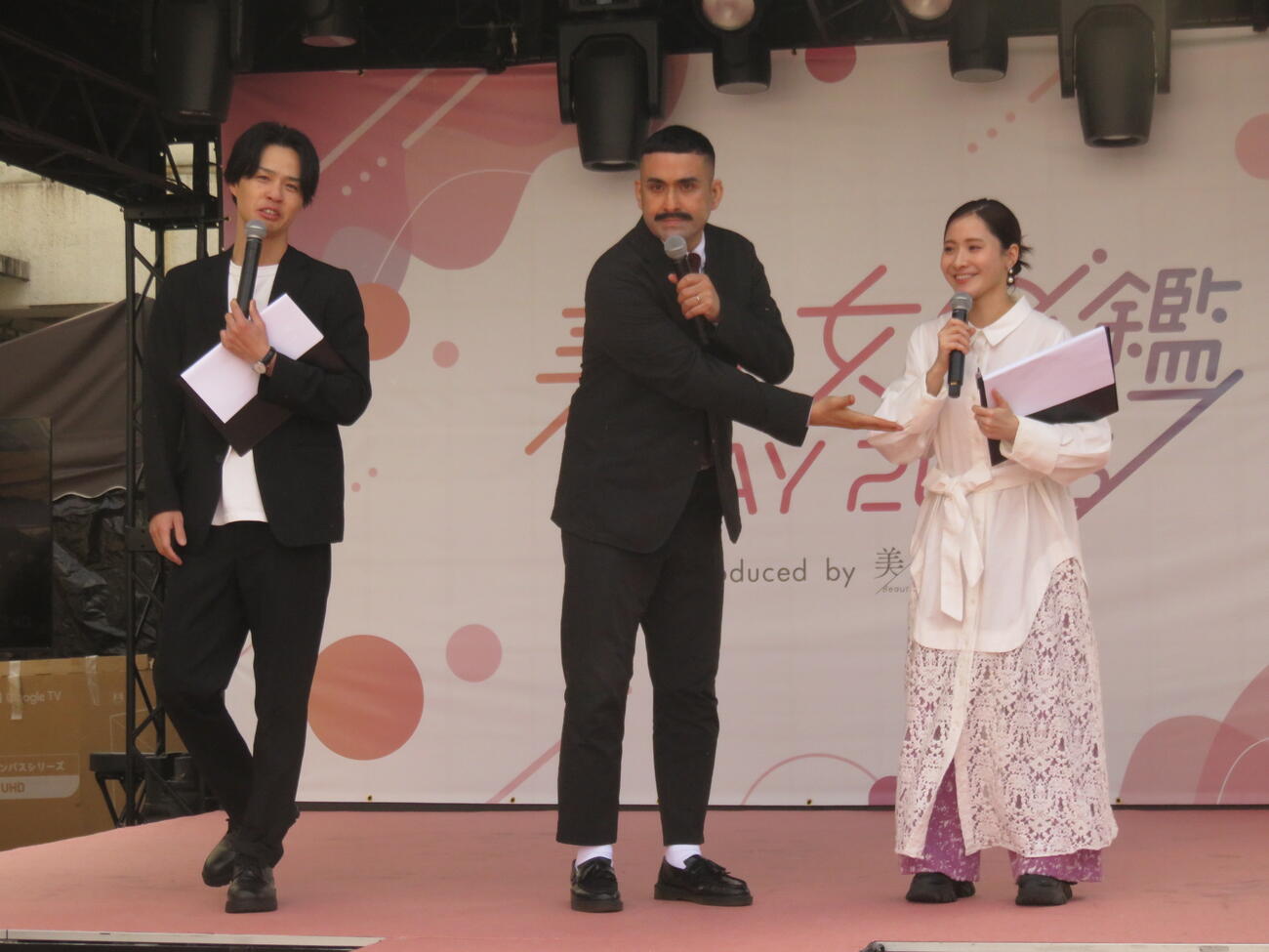 デニス植野行雄（中）は妻の比嘉梨乃（右）を紹介する。左は松下宣夫
