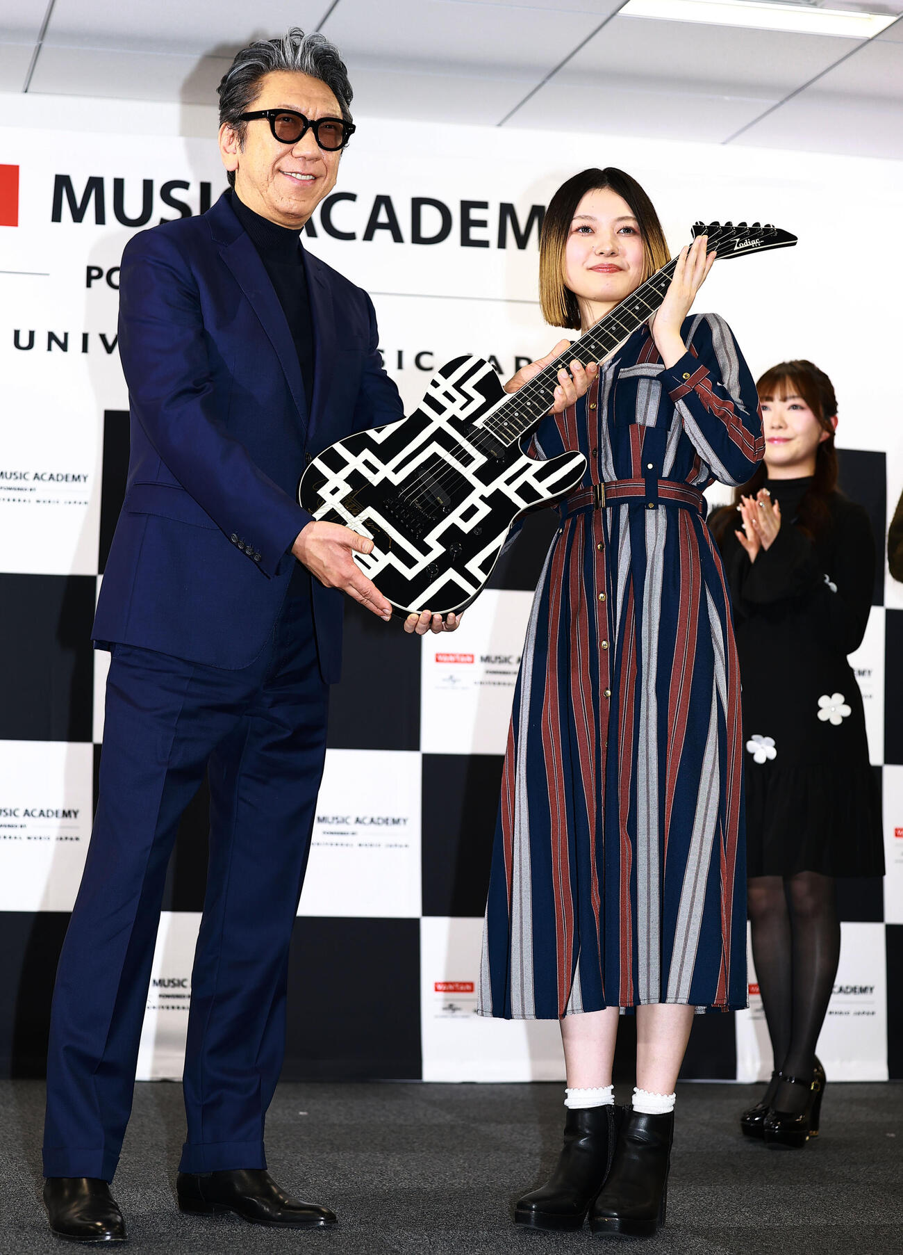 「バンタンミュージックアカデミー　POWERED BY　ユニバーサルミュージック」の開校イベントに登場した特別顧問の布袋寅泰（左）は、入校予定の代表者にギターを贈呈（撮影・野上伸悟）