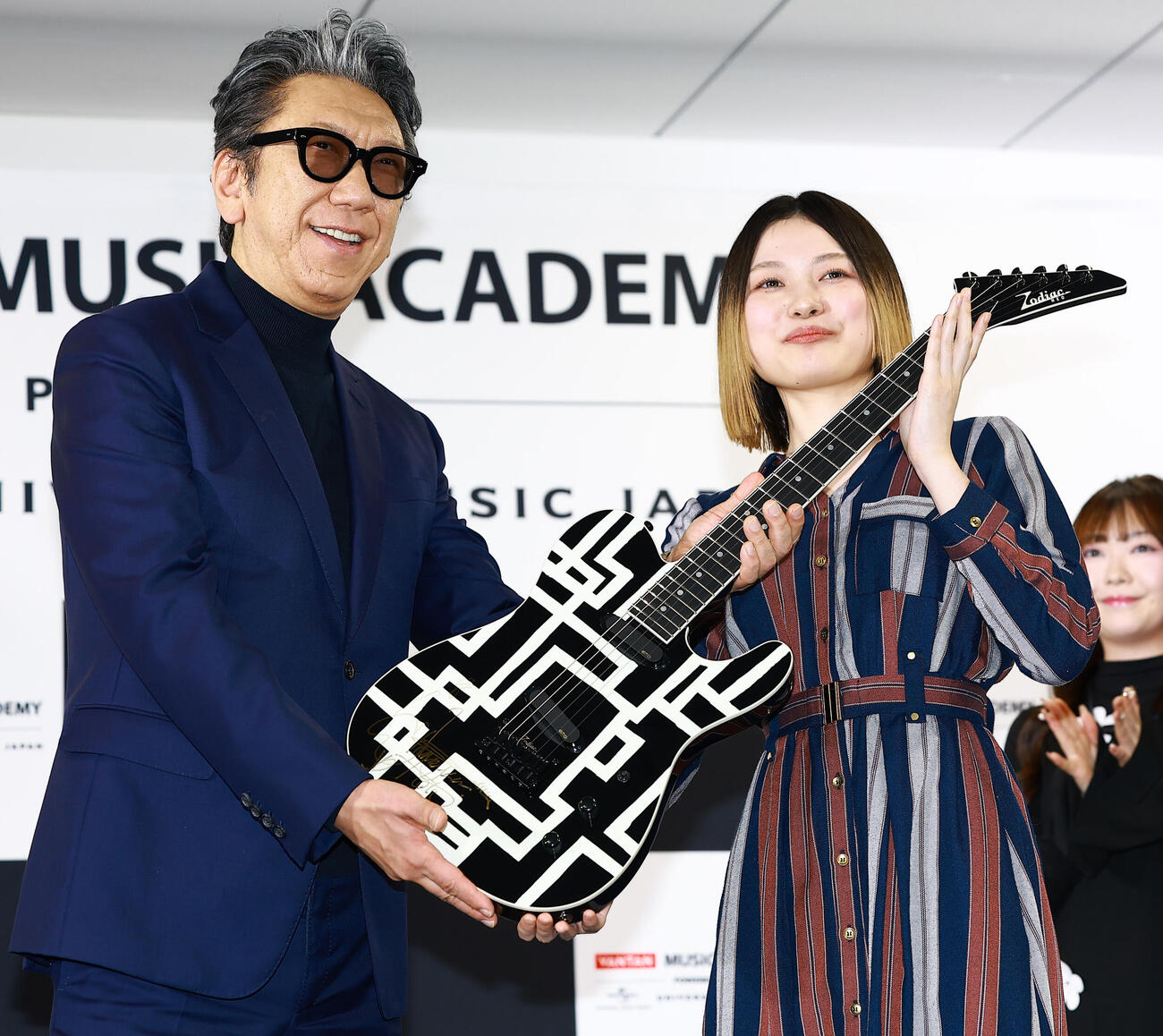 「バンタンミュージックアカデミー　POWERED BY　ユニバーサルミュージック」の開校イベントに登場した特別顧問の布袋寅泰（左）は、入校予定の代表者にギターを贈呈（撮影・野上伸悟）