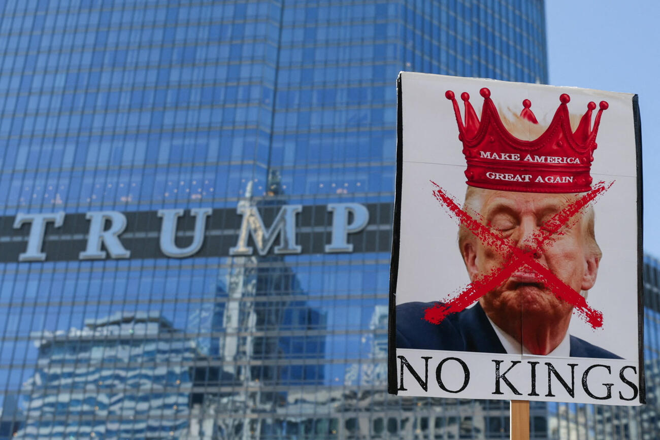 米イリノイ州シカゴで、トランプ政権の政策に反対する「No Kings」デモが行われ、デモ参加者がトランプ・タワーの前を通り過ぎる中、ある参加者がドナルド・トランプ米大統領を描いたプラカードを掲げている(ロイター)