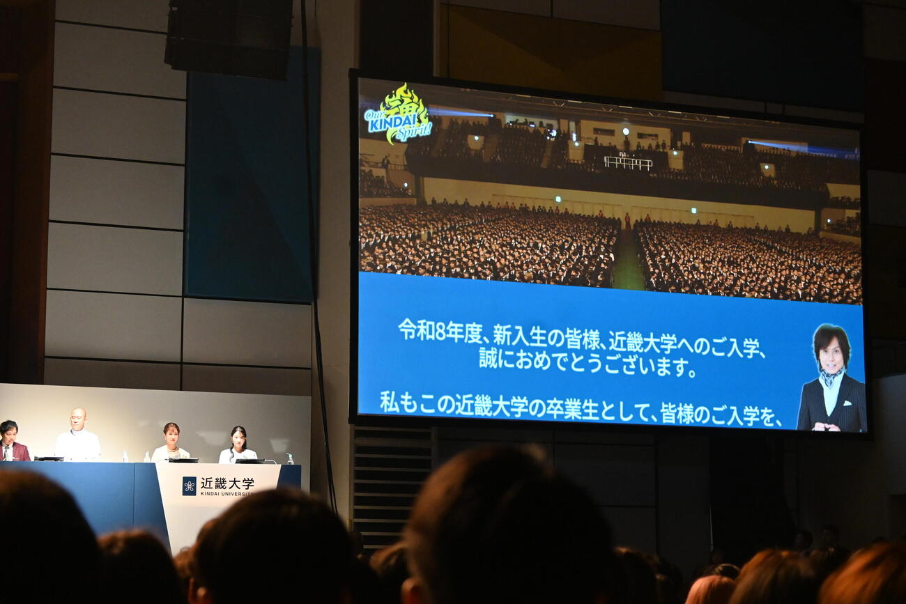 近大の入学式を体調不良で欠席したつんく♂はスクリーンを通じて新入生にメメッセージを送った（撮影・松浦隆司）