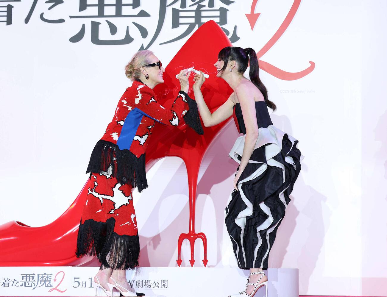 来日スペシャルイベントでハイヒールにサインをし、ペンをちょんとするメリル・ストリープ（左）とアン・ハサウェイ（撮影・増田悦実）