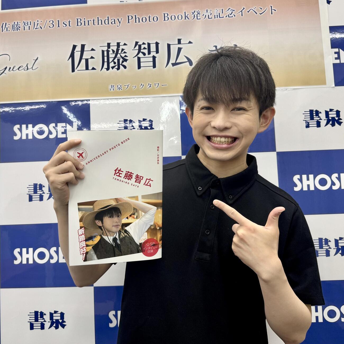 フォトブック「31st Birthday Photo Book」を手に笑顔を見せる佐藤智広