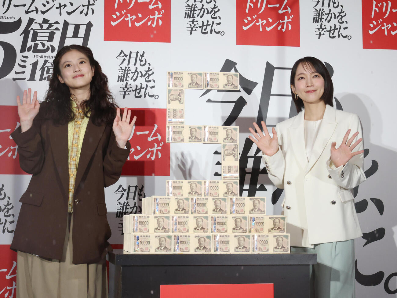 「ドリームジャンボ宝くじ」「ドリームジャンボミニ」発売記念イベントで5億円ダミー台の横で手を振る今田美桜（左）と吉岡里帆（撮影・増田悦実）