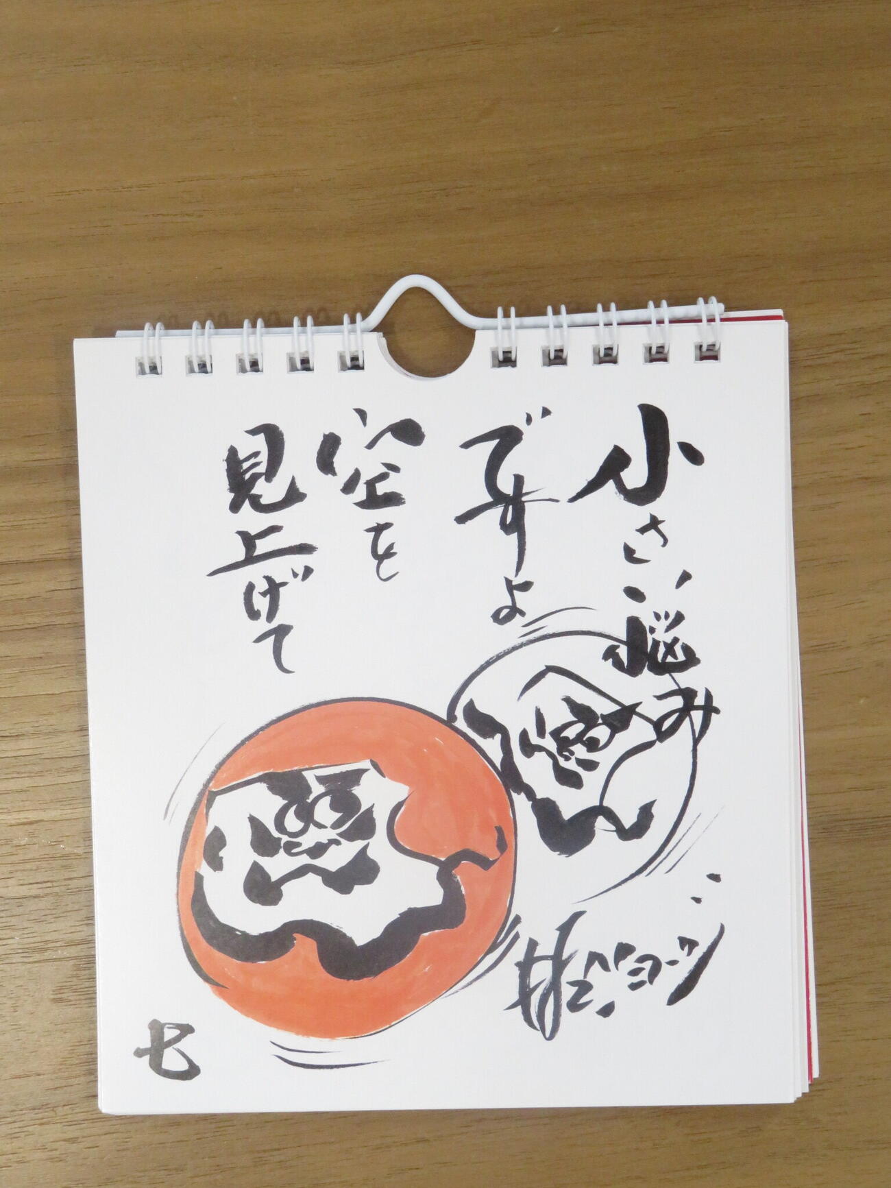 個展に飾られる村上ショージ直筆の「ダルマの絵」と「言葉」は、日めくりカレンダーとして発売予定。本人イチオシの言葉は「小さい悩みですよ　空を見上げて」