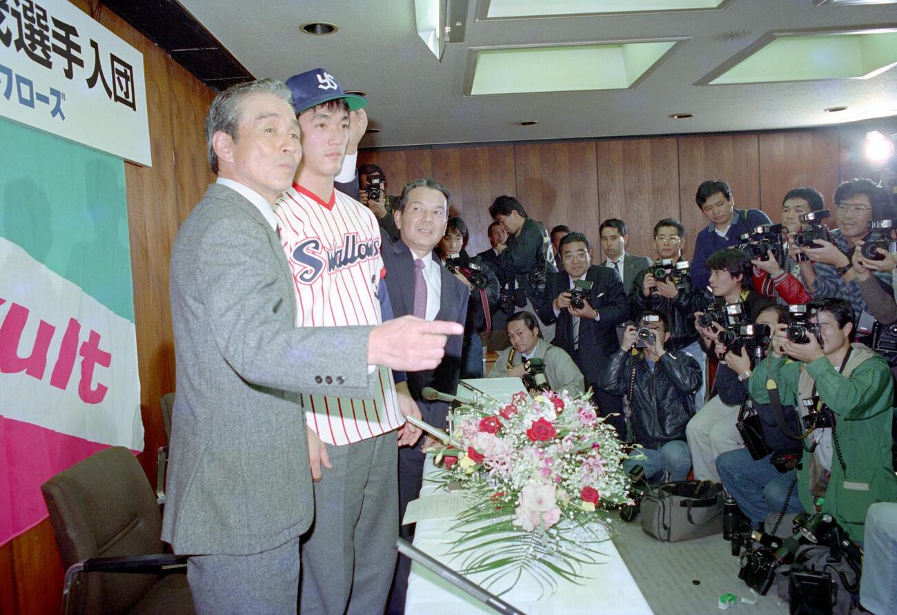 1987年11月、長嶋一茂ヤクルト入団会見　約150人の報道陣が見守る中、背番号3のユニホーム姿で記念撮影する長嶋一茂（左から2人目）。左端は関根潤三監督