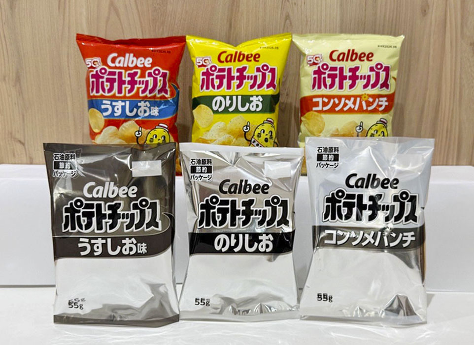 白と黒の2色に変更されたカルビー「ポテトチップス」の包装（手前）と従来の商品。中東情勢悪化によるナフサ不足を受け、同社は5月下旬出荷分から順次包装を変更すると発表した（共同）