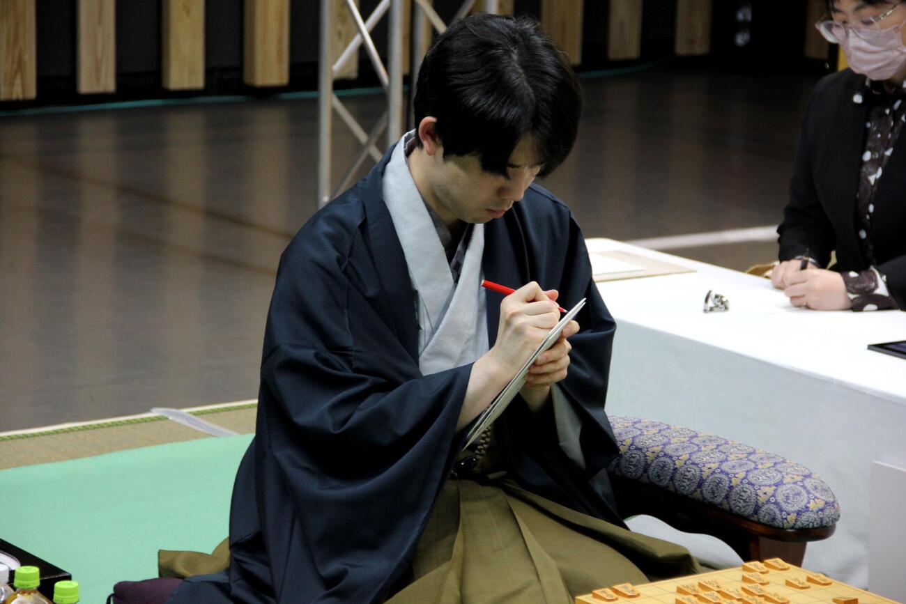 封じ手の封筒に確認をサインをする藤井聡太名人（日本将棋連盟提供）