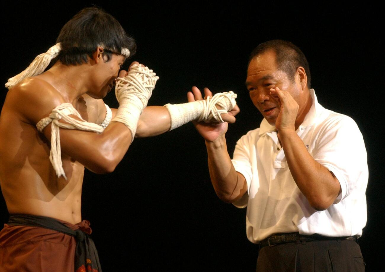 マッハ！の試写会で主演のトニー・ジャー（左）のパンチを受けるガッツ石松＝2004年7月18日（電子カメラ）