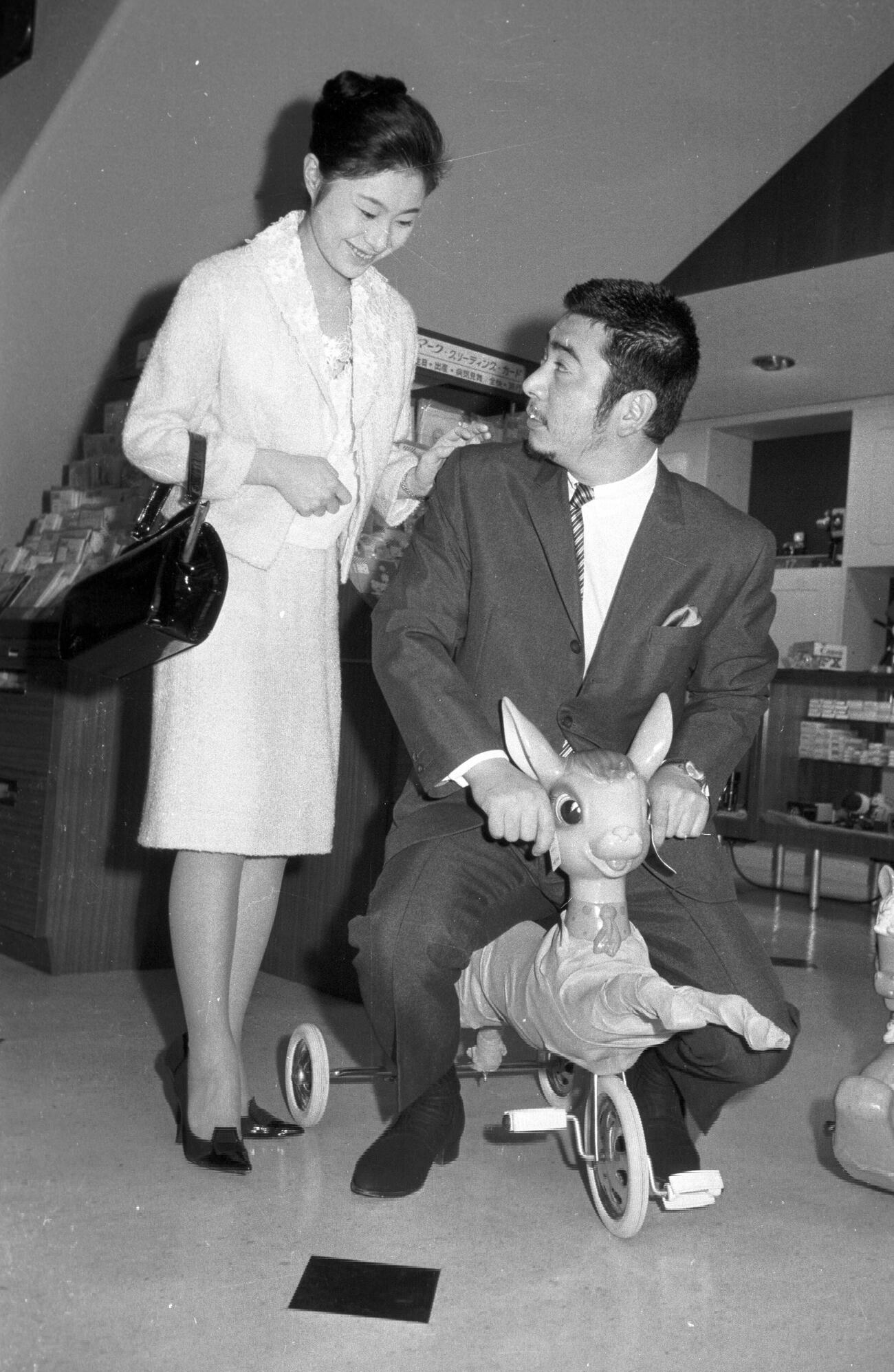 子ども用遊具に乗っておどける勝新太郎さん（右）とほほ笑む中村玉緒さん（1965年撮影）