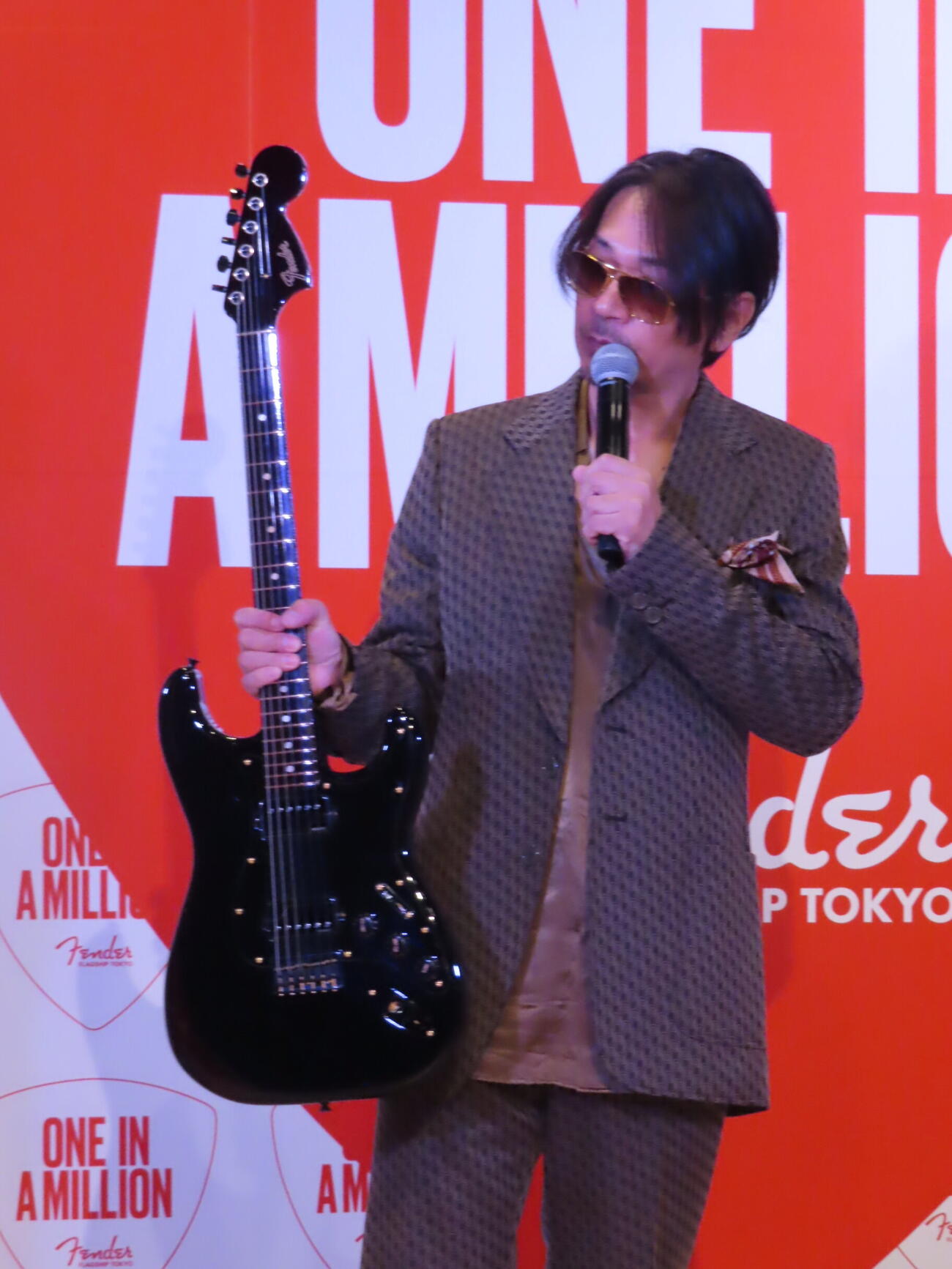 「フェンダー・フラッグシップTokyo来店100万人～スペシャルセレブレーション」で自身のシグネイシャーモデルを手に紹介するラルクアンシェルのKen