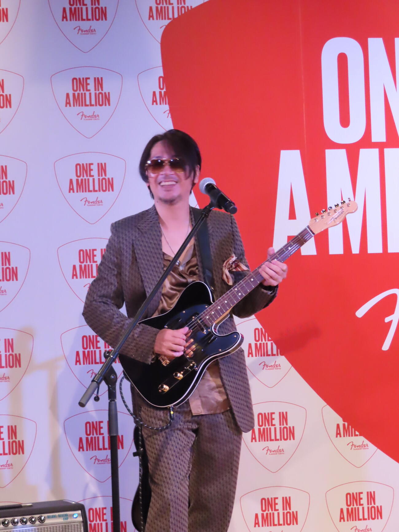 「フェンダー・フラッグシップTokyo来店100万人～スペシャルセレブレーション」で100万人目の来店者にプレゼントされるギターを弾くラルクアンシェルのKen
