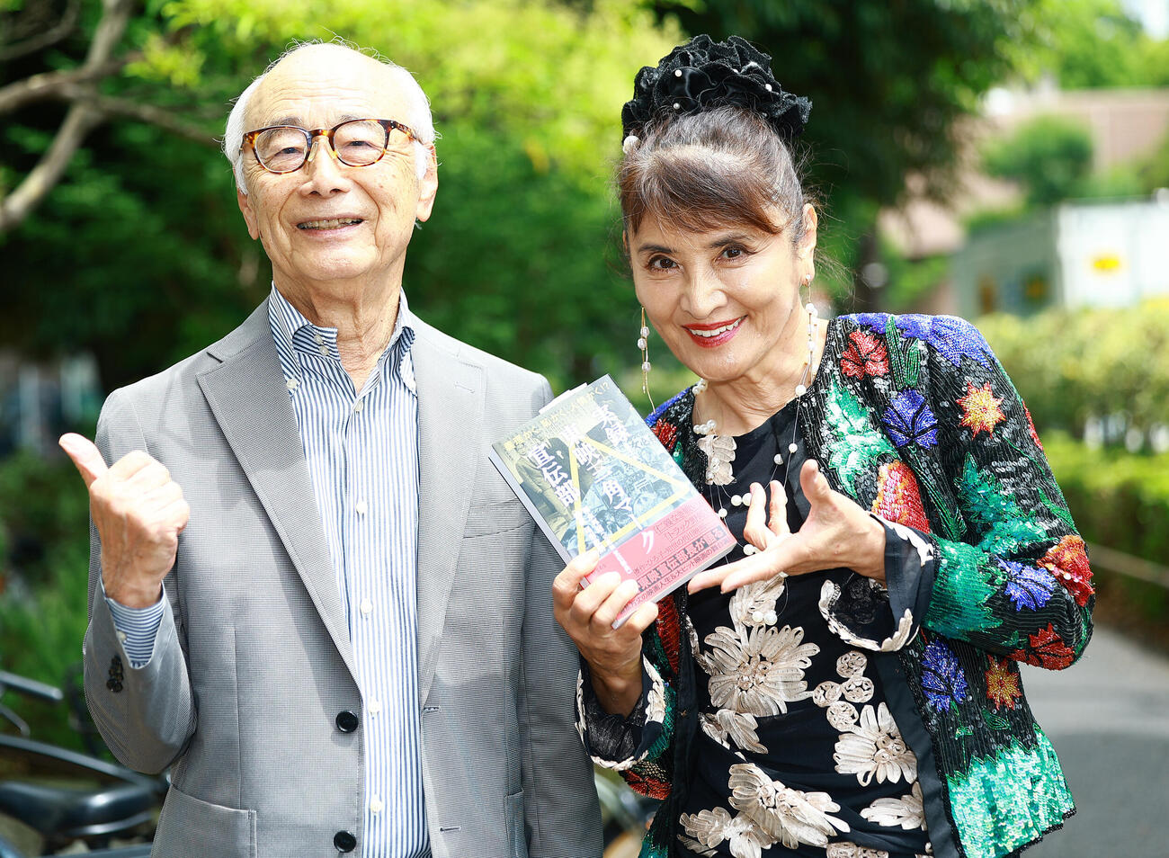 福永邦昭さん（左）が出す本を手に笑顔をみせる志穂美悦子さん（撮影・野上伸悟）