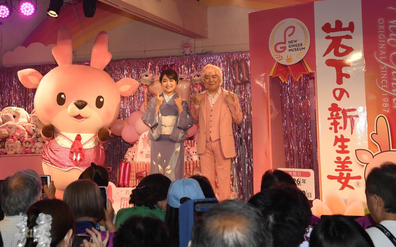 岩下食品の公式キャラクター「イワシカちゃん」と岩下和了社長にはさまれて笑顔を見せる平山花羽