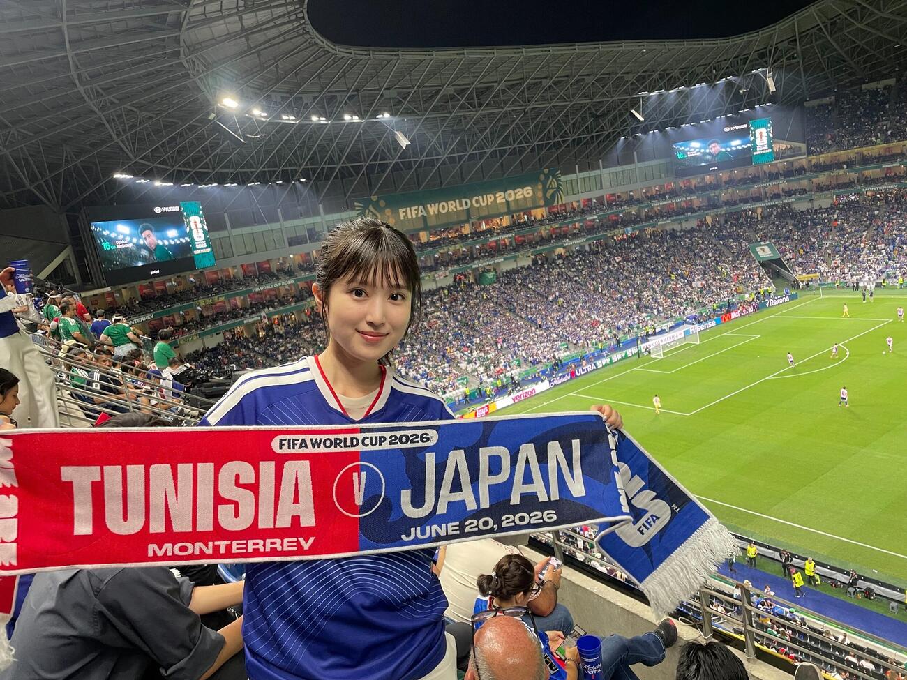 レプリカユニホームを着て、現地で手に入れた限定タオルを手に、サッカーW杯日本－チュニジア戦をメキシコで観戦した福本莉子（本人提供）