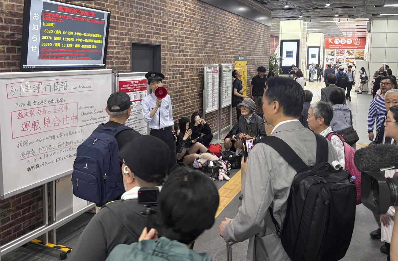 地震の影響で運転見合わせとなった列車の運行情報を説明する駅員＝25日午前8時35分、JR盛岡駅（共同）