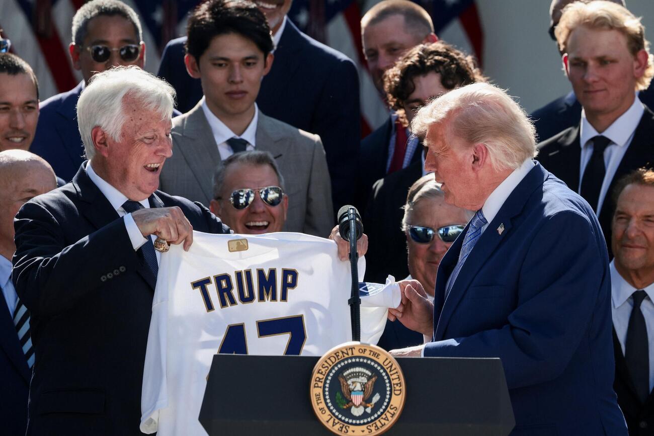 ドジャースオーナーのマーク・ウォルター氏から名前と第47代大統領を表す背番号が付いたユニホームをプレゼントされるトランプ米大統領。奥は佐々木朗希（ロイター）