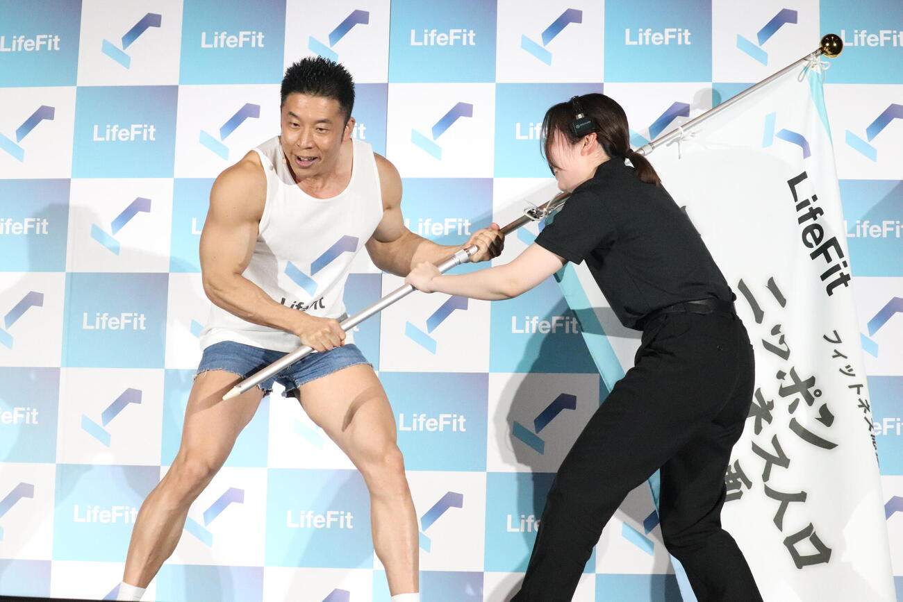 LifeFit「フィットネス応援部長」就任イベントで、スタッフと旗の取り合いをするなかやまきんに君