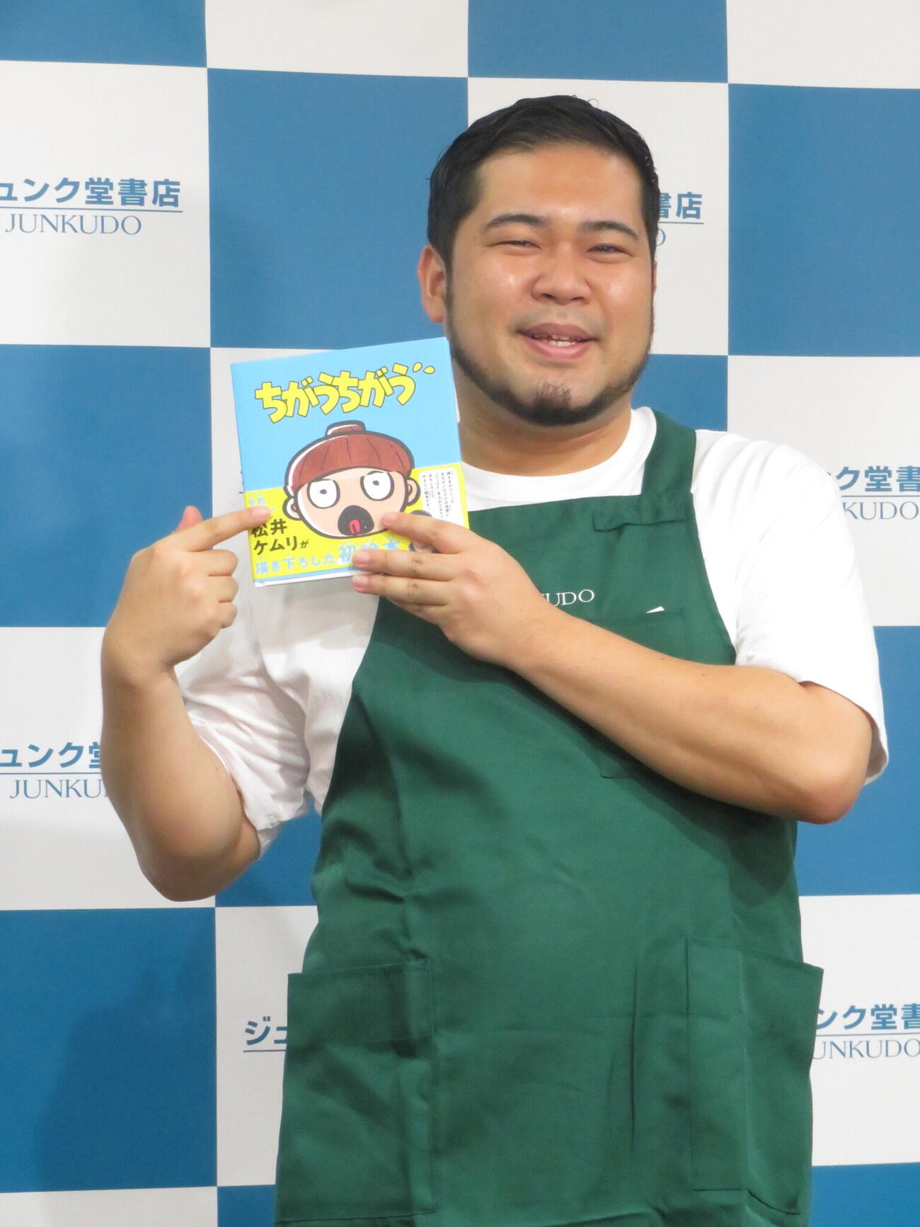 初めて出版した絵本「ちがうちがう」を手に笑顔を見せる松井ケムリ