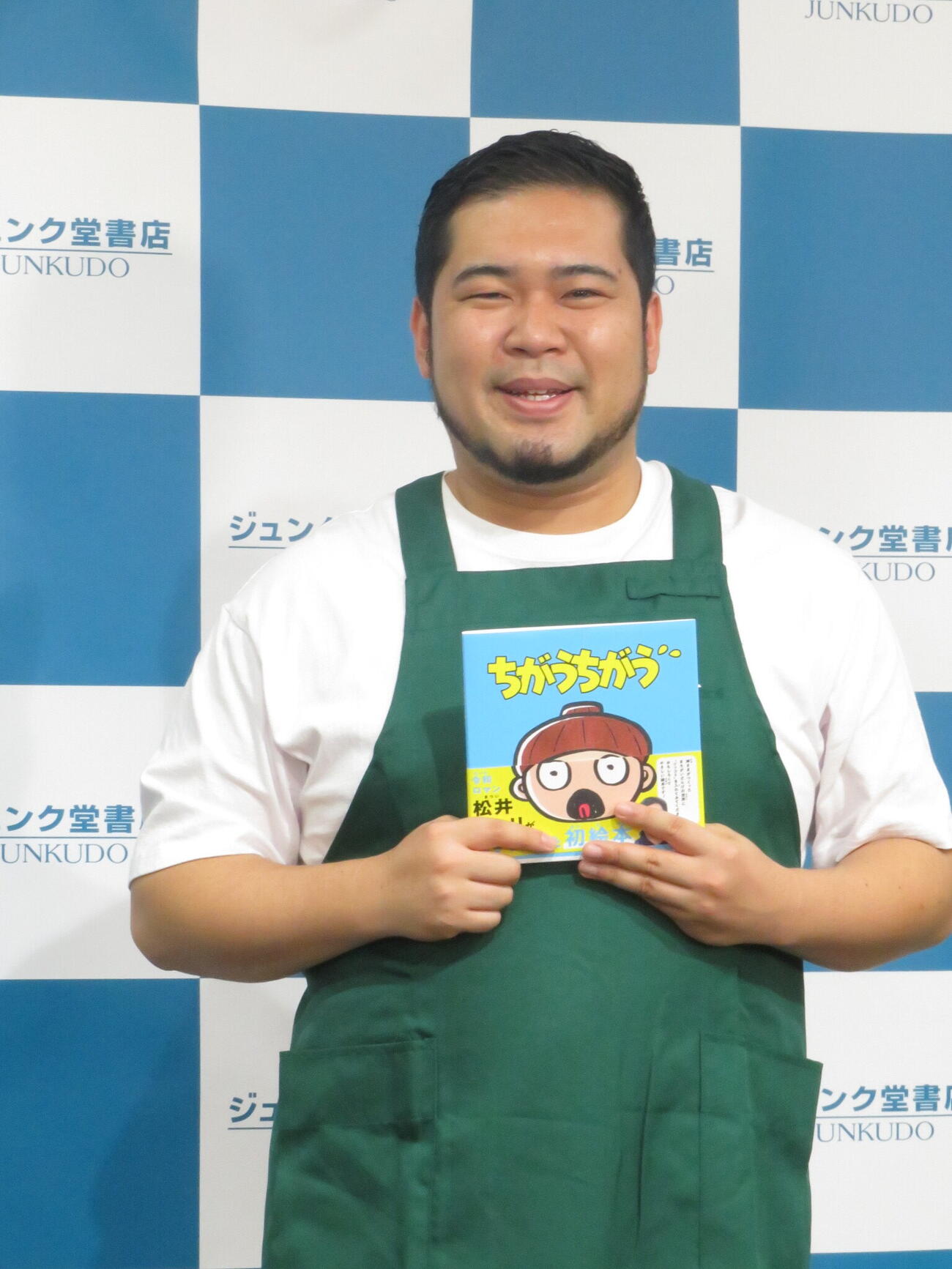 初めて出版した絵本「ちがうちがう」を手に笑顔を見せる松井ケムリ