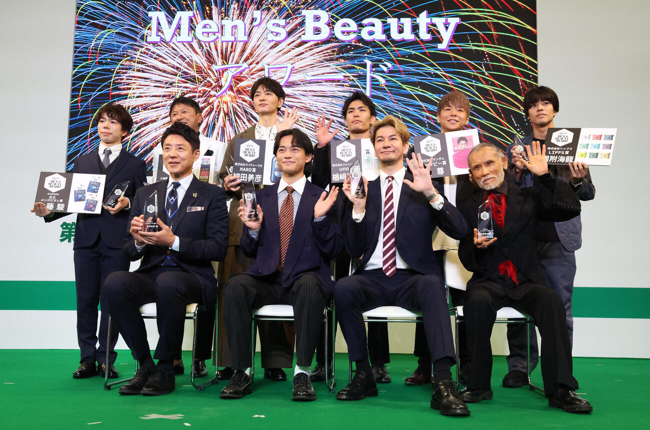 第6回Men's BeautyアワードでTVカメラに向かって手を振る受賞者の、前列左から松岡修造、中山翔貴、JOY、片岡鶴太郎。後列左から佐藤駿、武田修宏、細田義彦、楢崎智亜、武尊、根附海龍（撮影・丹羽敏通）